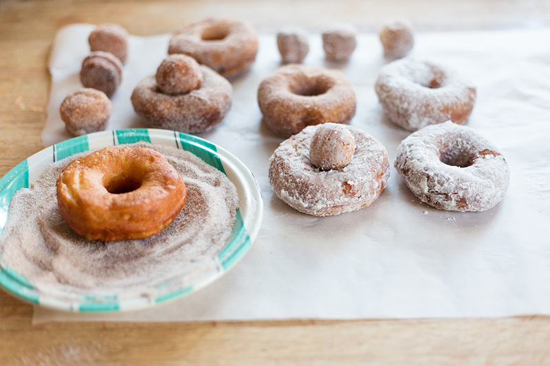 finished biscuit donuts being dipped in cinnamon sugar