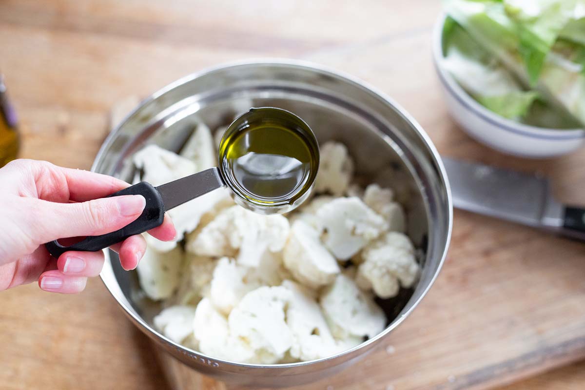 adding oil to cauliflower florets