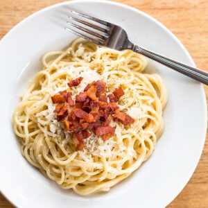 Pasta carbonara topped with bacon.