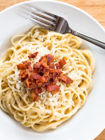 Pasta carbonara topped with bacon.