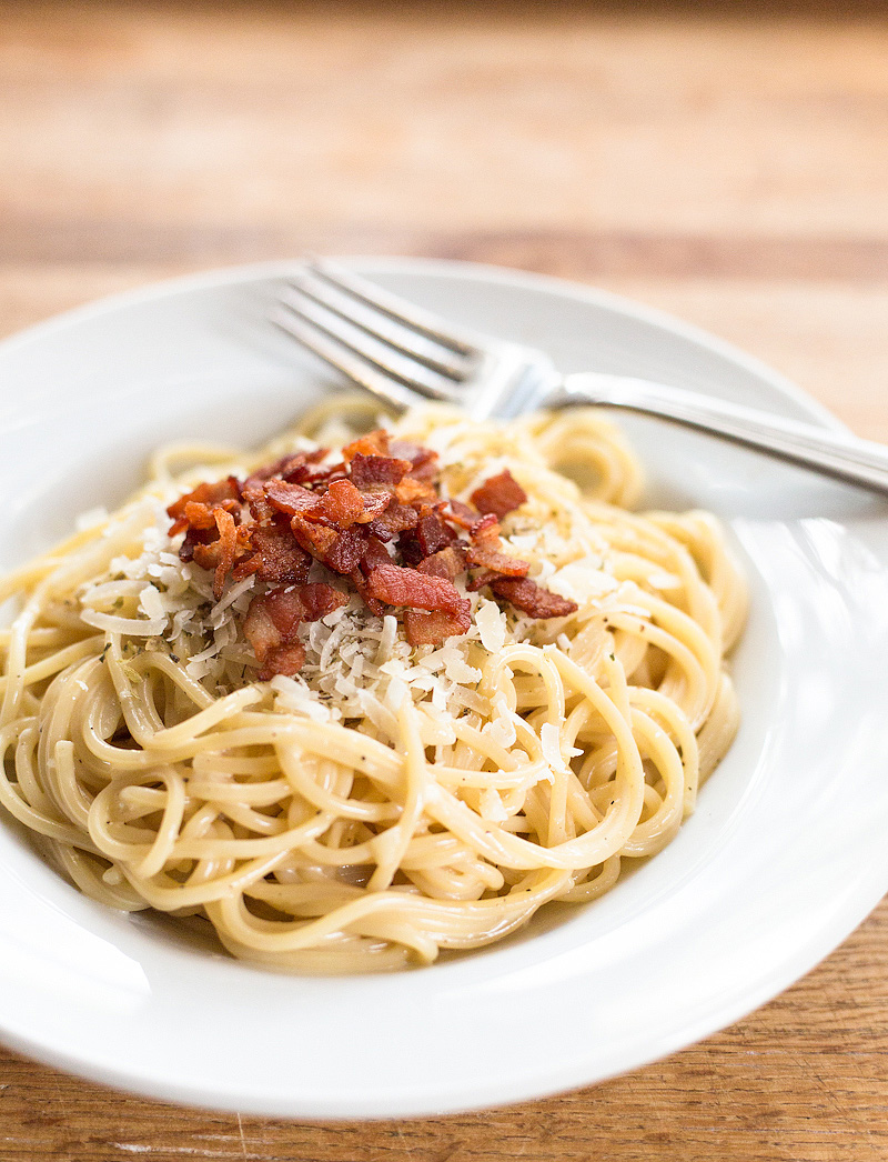 Spaghetti carbonara topped with bacon and cheese.