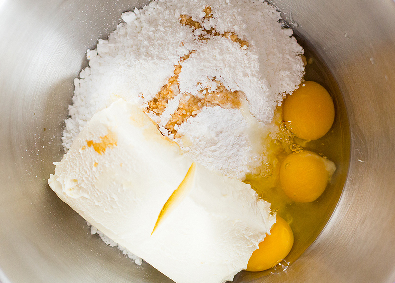 cream cheese, eggs, and powdered sugar in a bowl