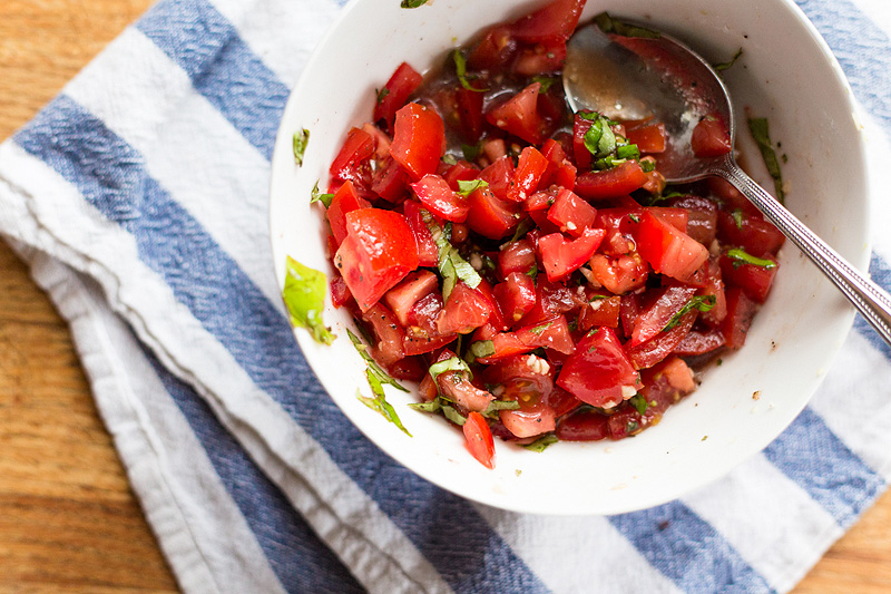 tomatoes for bruschetta in a white bowl mixed with garlic and oil