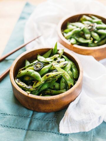 Edamame in a wooden bowl with jalapenos.