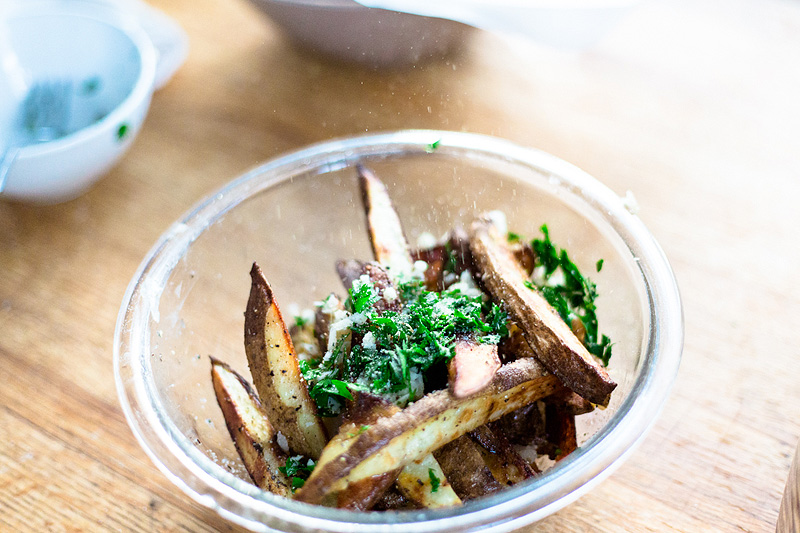 Adding garlic and parsley to french fries.