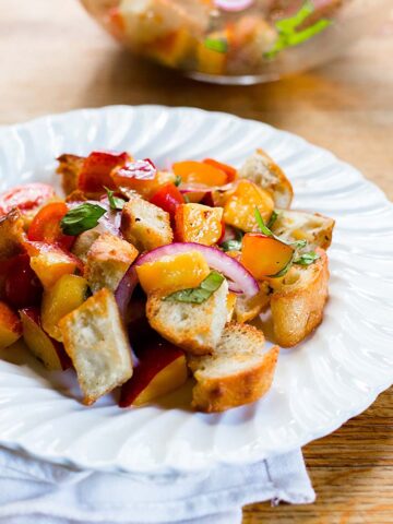 Peach panzanella on a white plate.