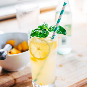 Peach cocktail in a glass with fresh basil.