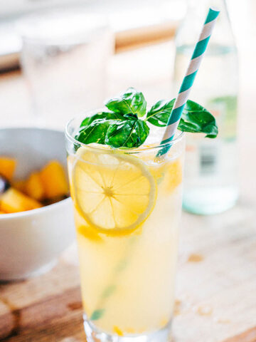 Peach cocktail in a glass with fresh basil.