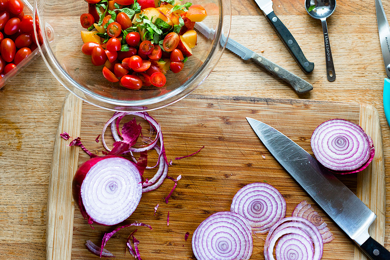 peaches, tomatoes and basil in a bowl with sliced red onion