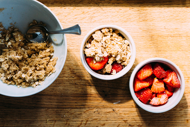 adding crumble topping to strawberries