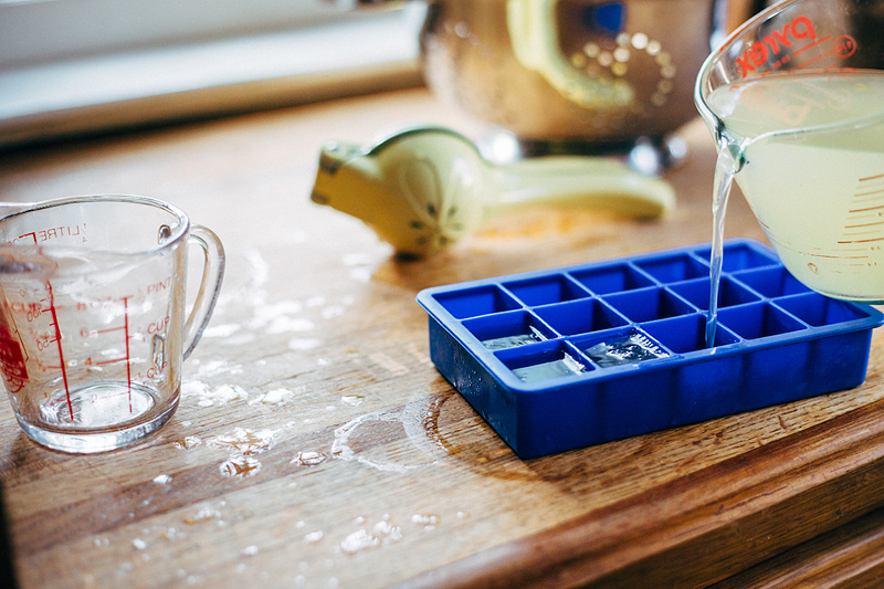 pouring lemon juice into an ice tray