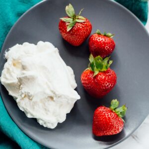 Strawberries and whipped cream on a plate.