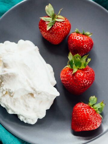 Strawberries and whipped cream on a plate.