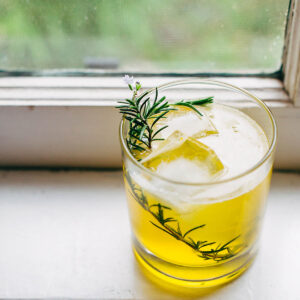 Bees knees cocktail in a class with a rosemary sprig for garnish