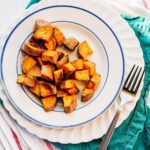 Coconut oil roasted sweet potatoes on a white and blue plate.