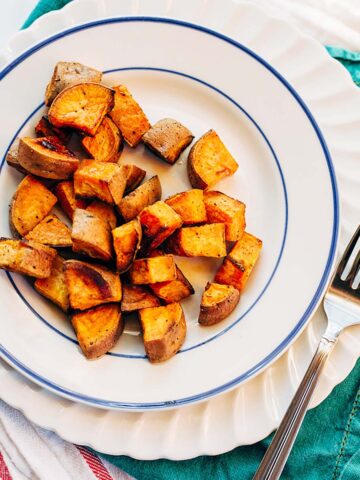 Coconut oil roasted sweet potatoes on a white and blue plate.