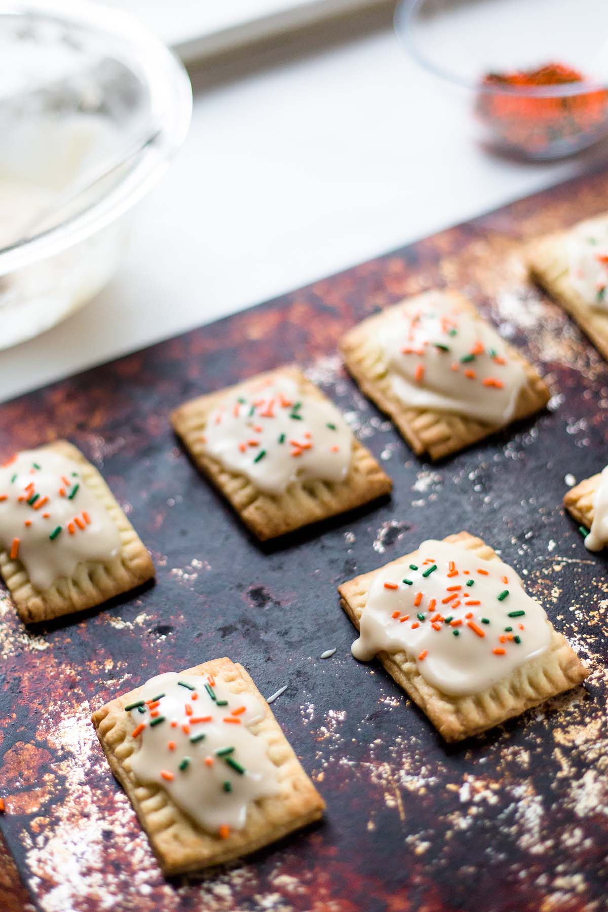 mini pumpkin pie pop tarts with sprinkles on a baking sheet