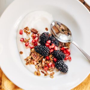 Yogurt topped with granola, blackberries, and pomegranate.