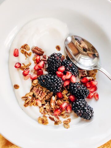 Yogurt topped with granola, blackberries, and pomegranate.