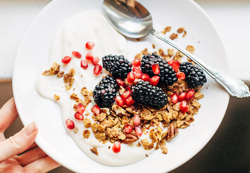 granola, yogurt, blackberries, and pomegranate seeds on a plate