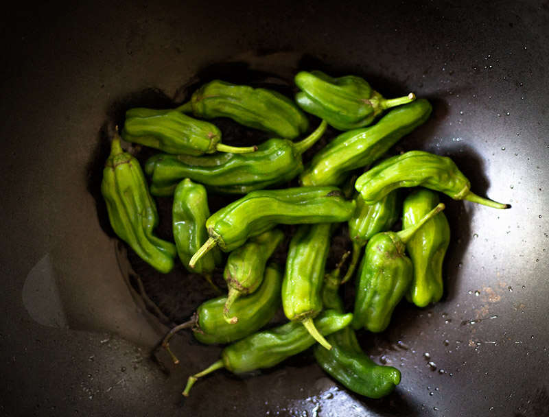 Blistered Shishito Peppers in a wok.