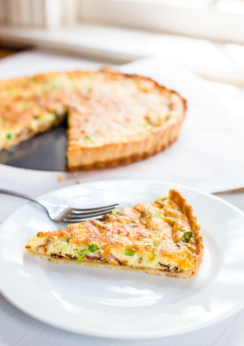 slice of bacon and pea quiche on a plate