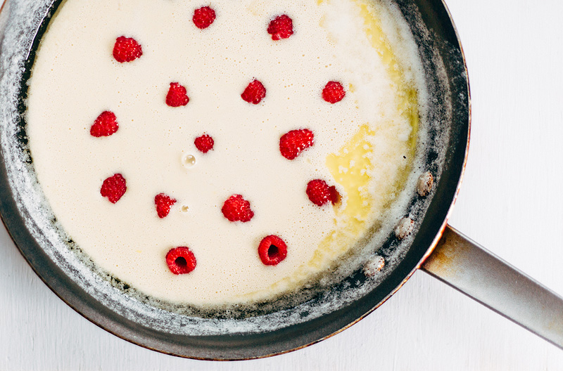 Raspberry Dutch Baby Pancake batter in a skillet with fresh raspberries