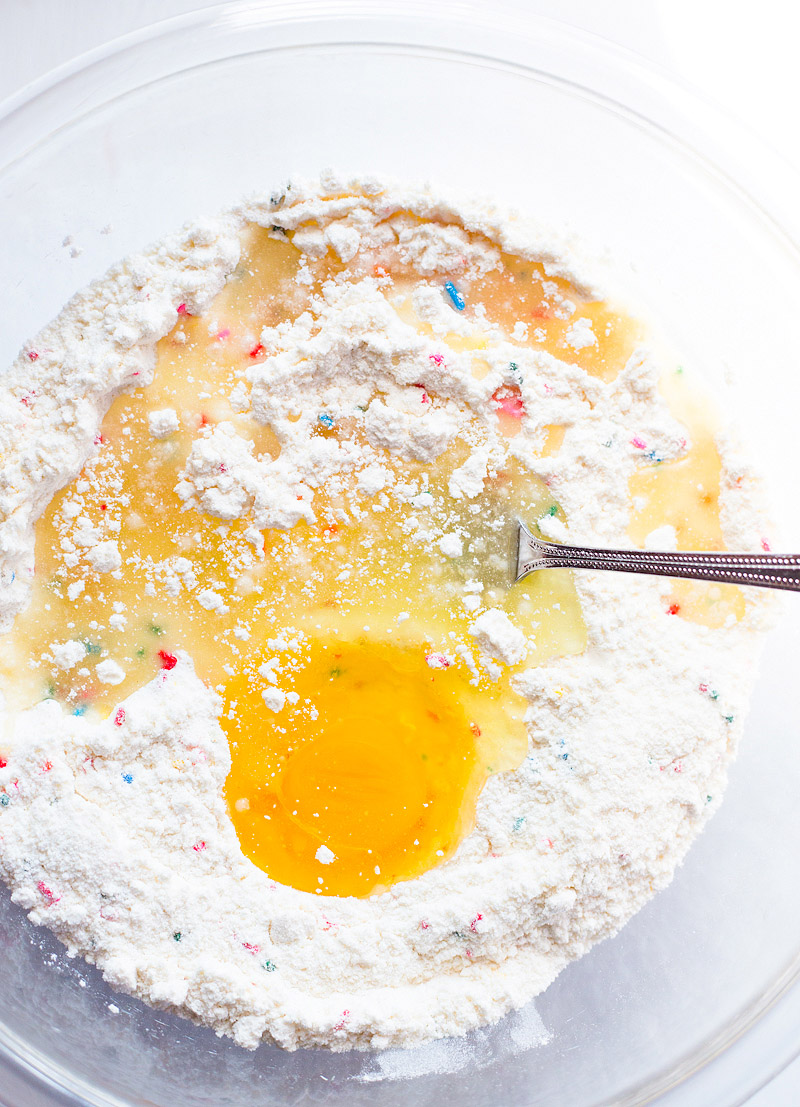 mixing together cake mix, sprinkles, and egg