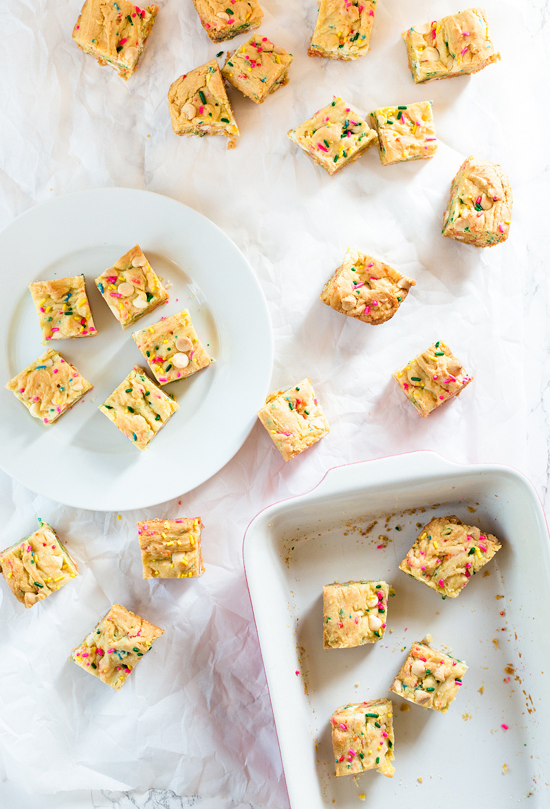 Gooey Confetti Cake Bars cut and spread out over parchment paper