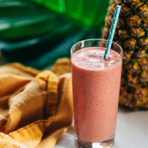 Tropical smoothie in a glass with pineapple in the background.