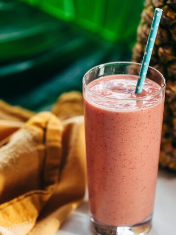 Tropical smoothie in a glass with pineapple in the background.