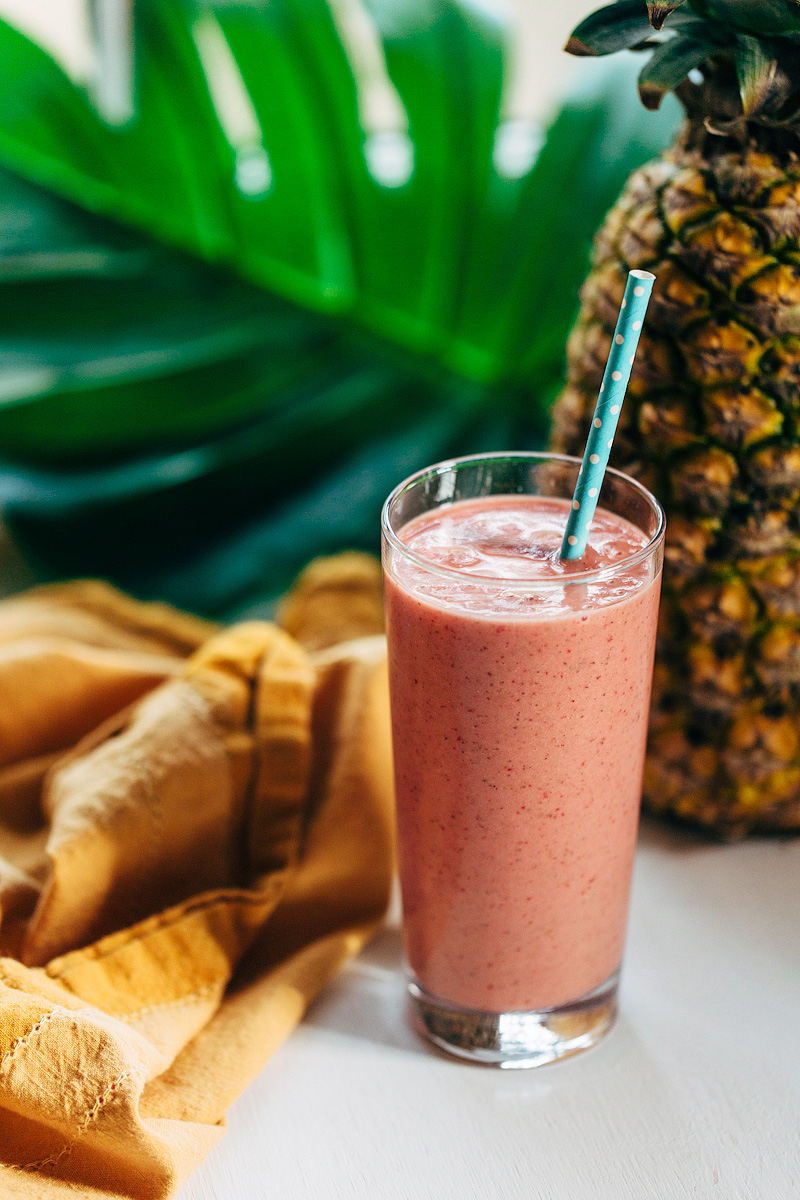 tropical smoothie in a glass with a pineapple in the background