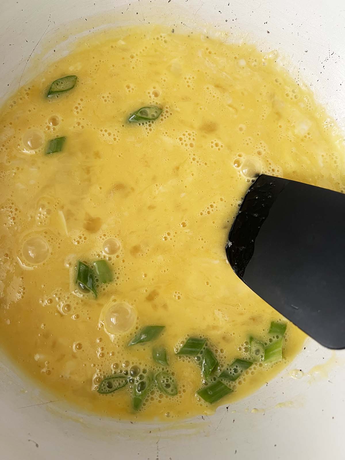 Eggs and green onions in a skillet.