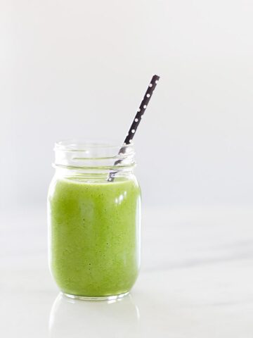 green smoothie in a mason jar with a black straw