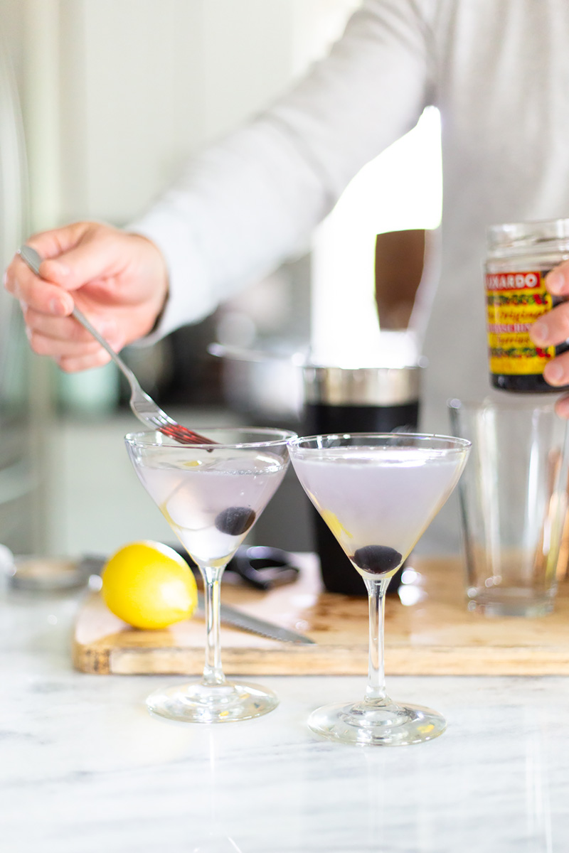 adding cherries to an aviation cocktail.