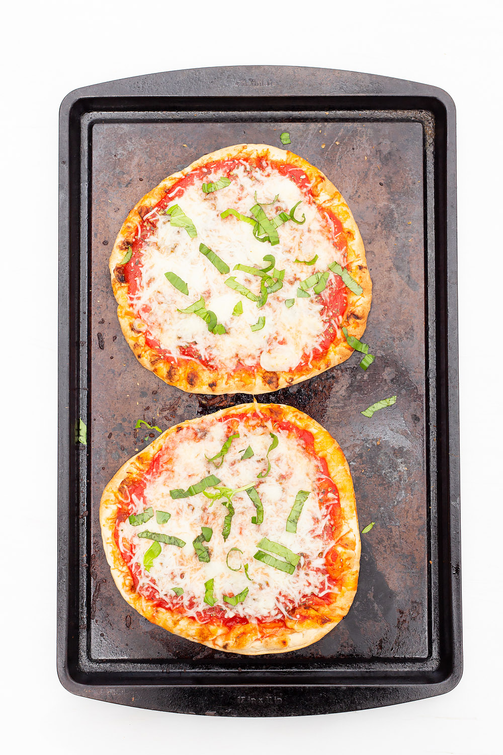 naan pizzas on a cookie sheet