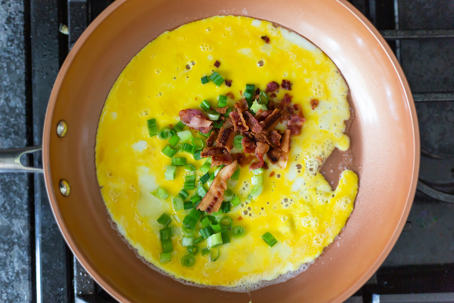 cooking eggs, bacon, and green onions.