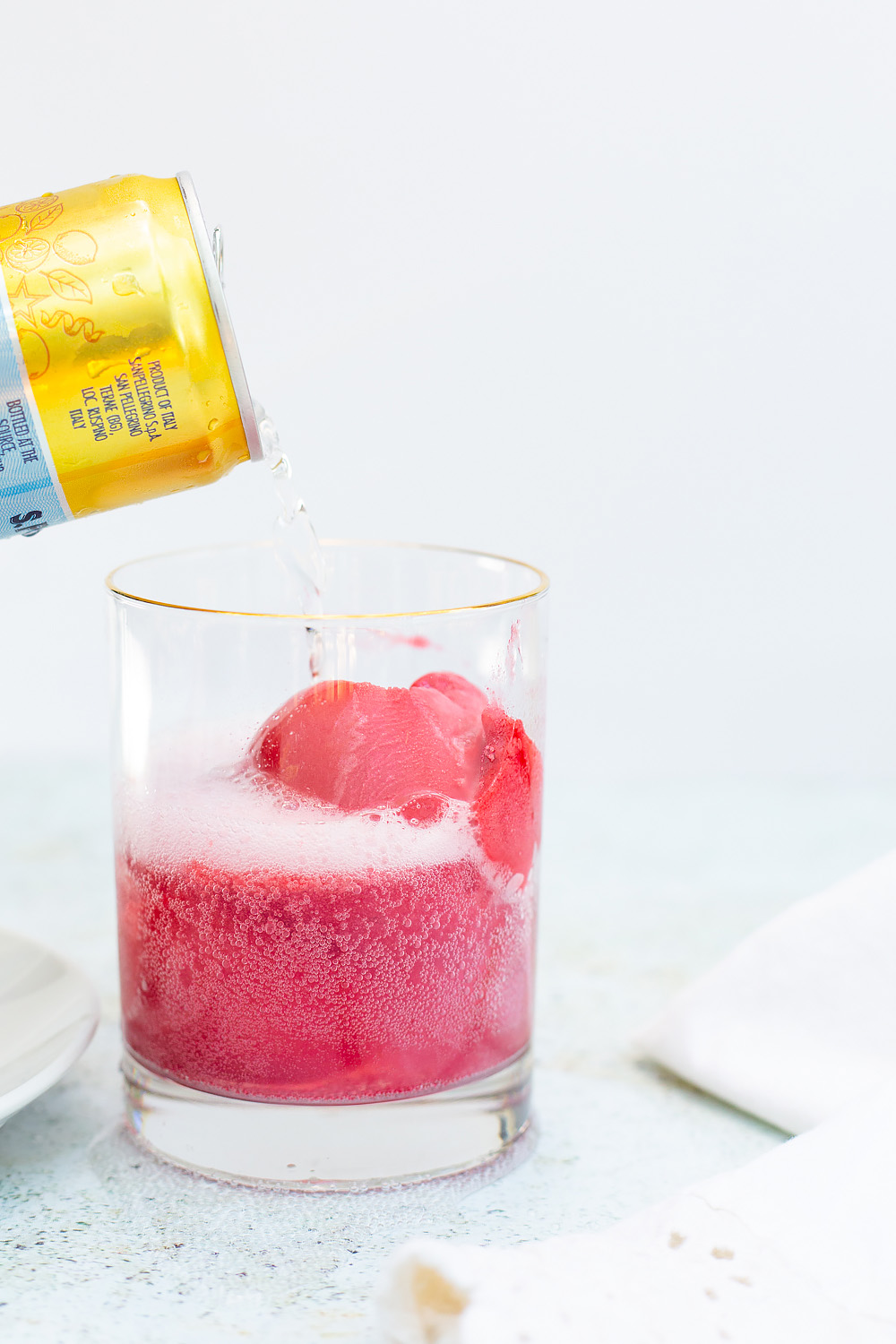 pouring lemon sparkling water into raspberry sorbet