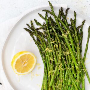 Roasted asparagus with lemon zest and a lemon on the side.