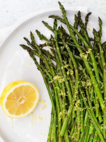 Roasted asparagus with lemon zest and a lemon on the side.