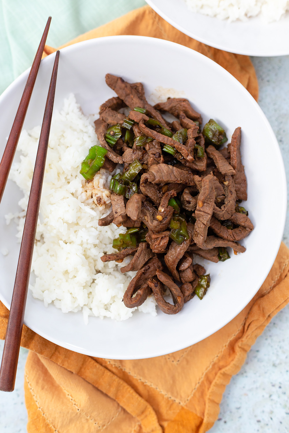 steak and sliced shishito peppers with chopsticks.