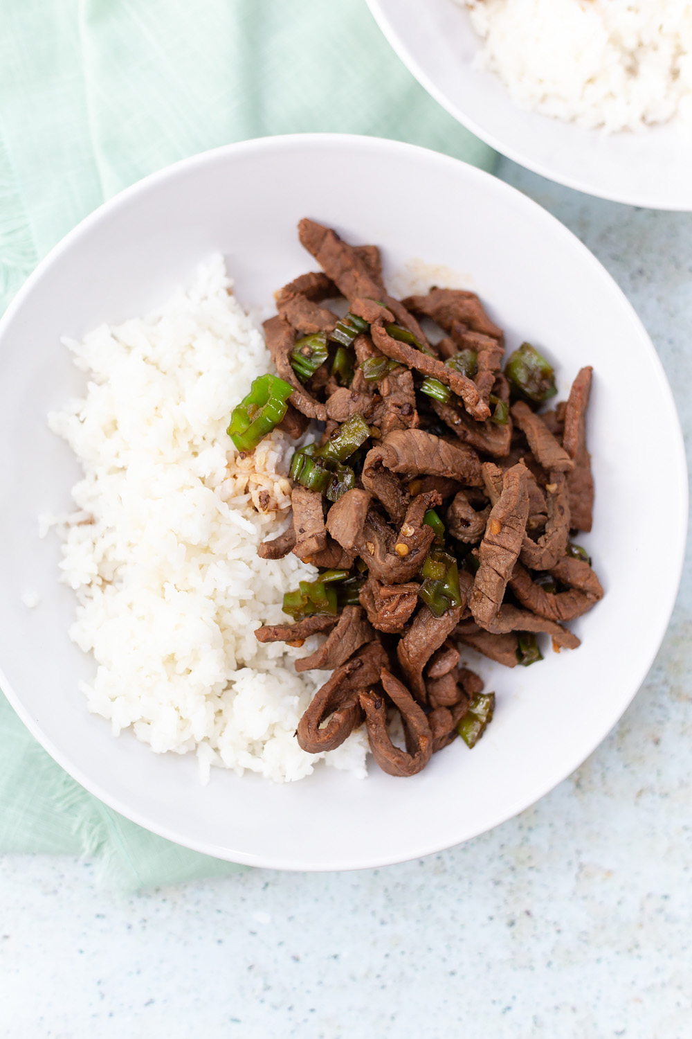 steak and shishito peppers in a bowl with rice on the side.