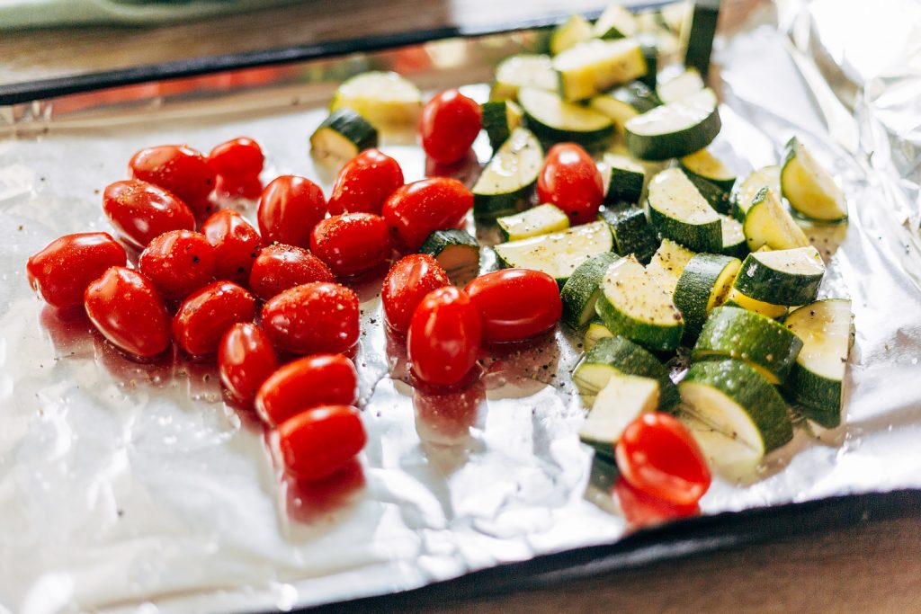 zucchini and tomatoes on a baking sheet