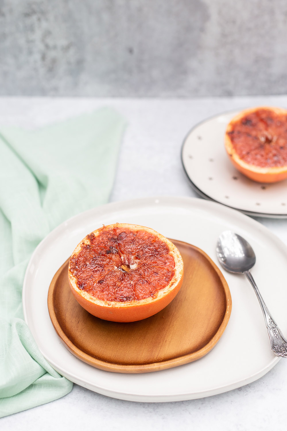 broiled grapefruit on a plate with another one in the background