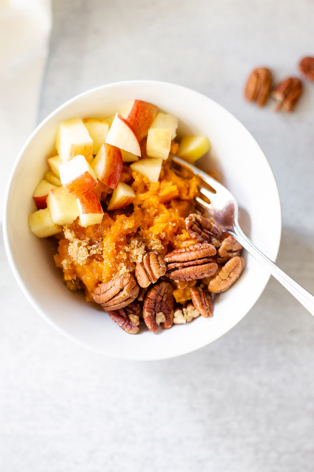 breakfast sweet potato bowl topped with apples and pecans