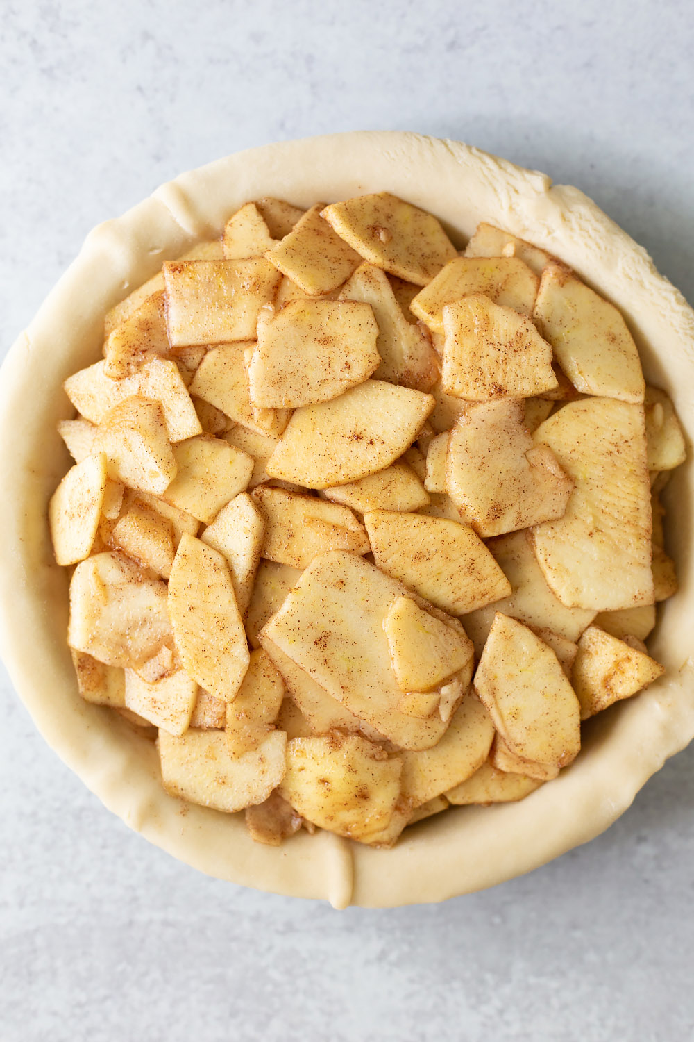 adding sliced apples to an apple pie