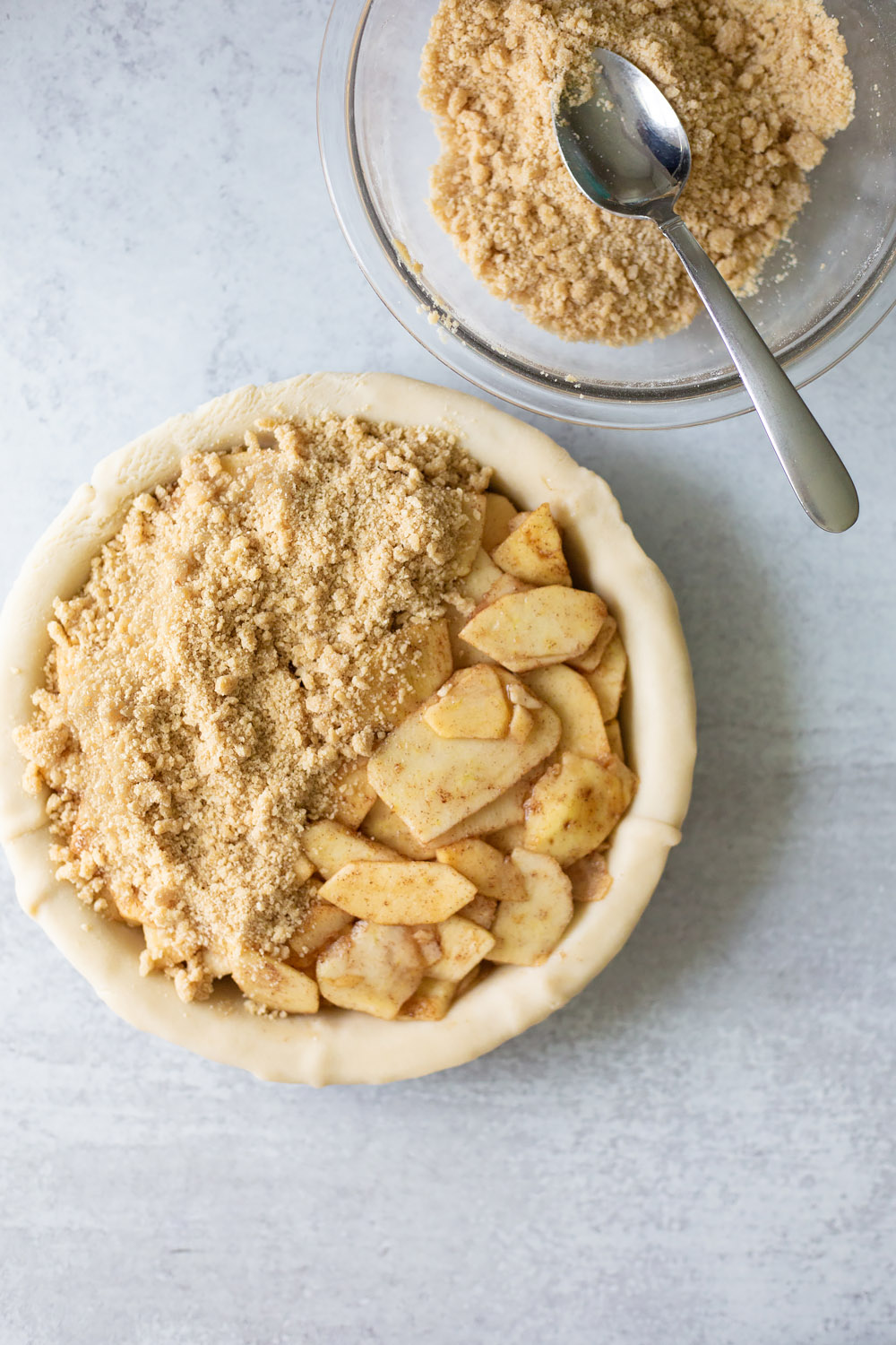 adding the crumble topping to a dutch apple pie