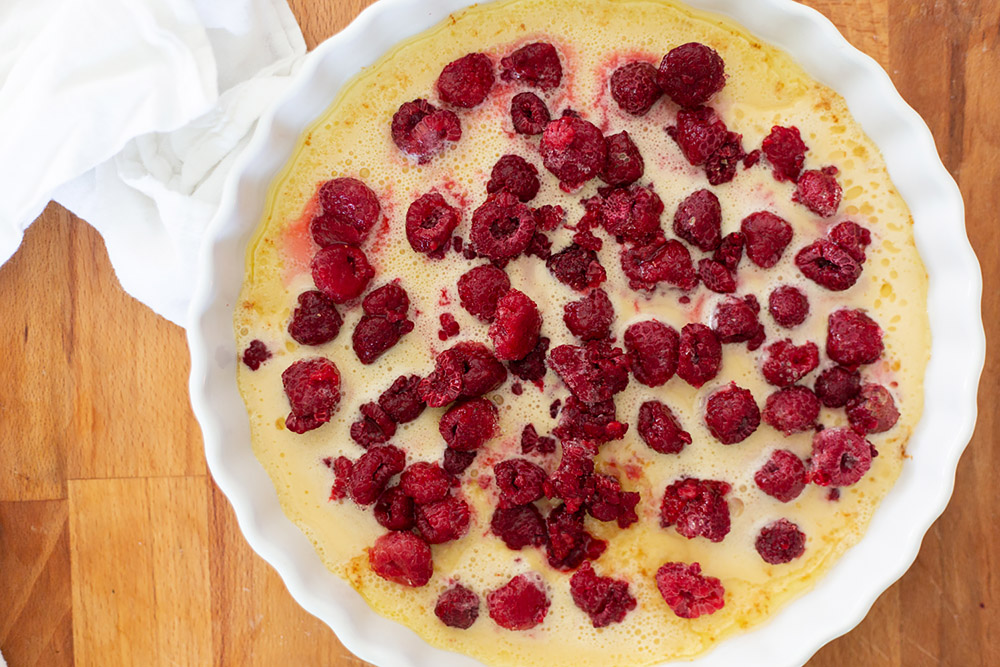 raspberries being added to clafoutis batter