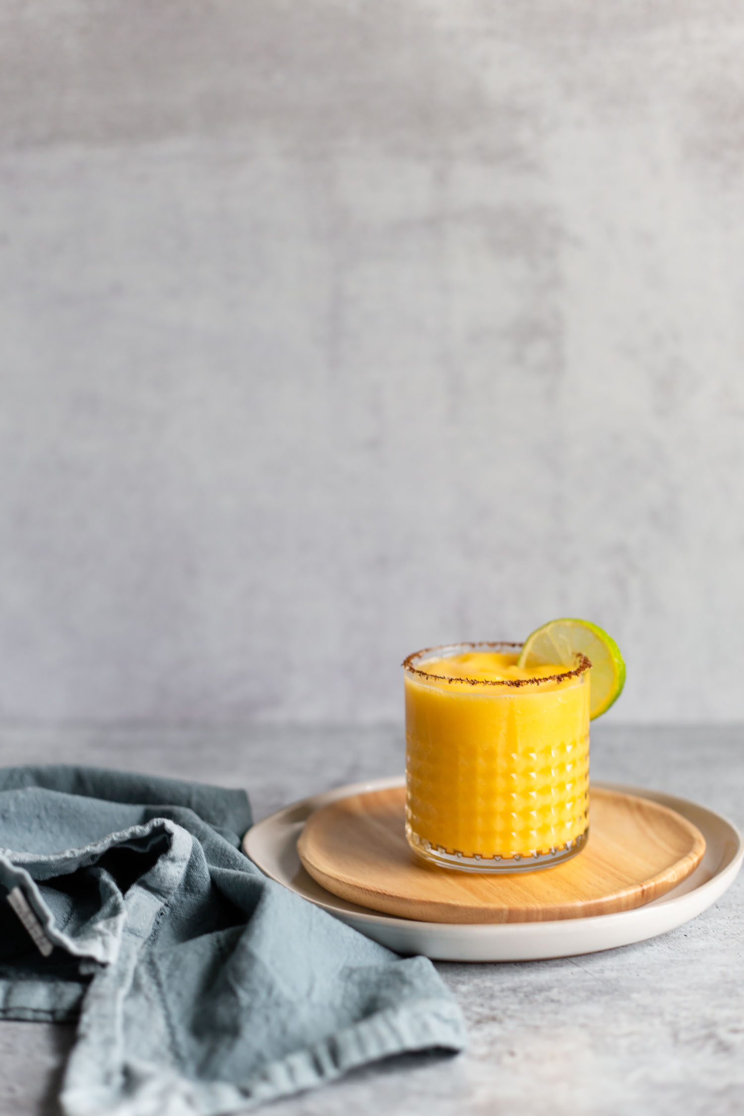 frozen mango margarita from the side with a blue napkin
