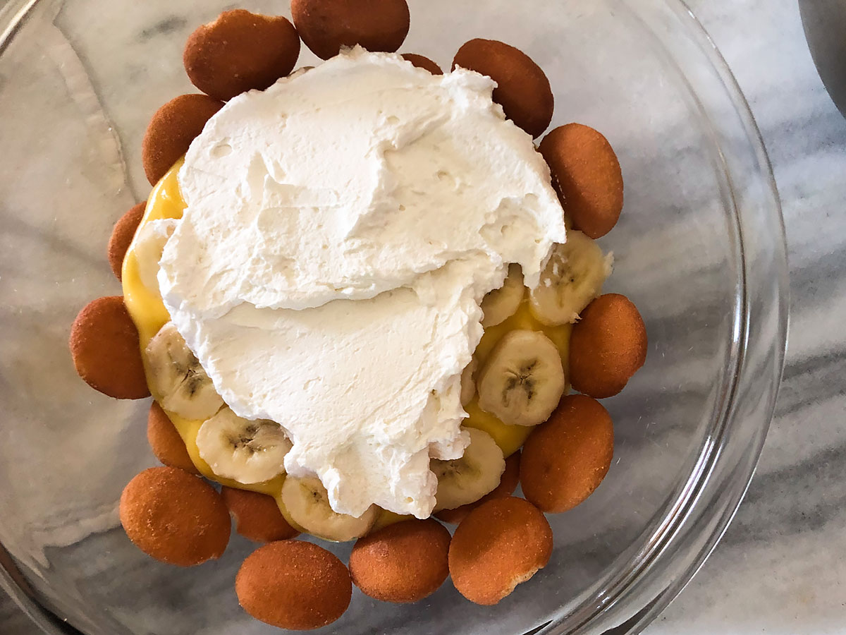 adding whipped cream to banana pudding